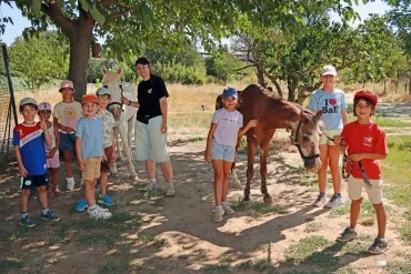 Un groupe d'enfants et leur animatrice promènent deux chevaux