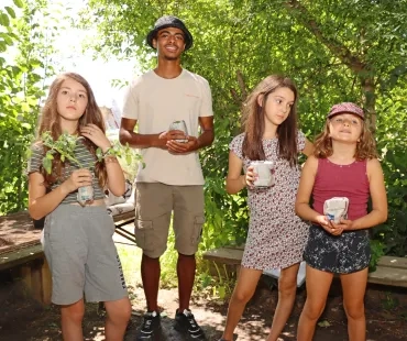 Un groupe d'enfants et leur animateur montrent des pots en papier journal