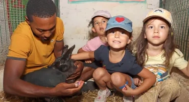 un groupe d'enfants et leur animateur caressent un lapin