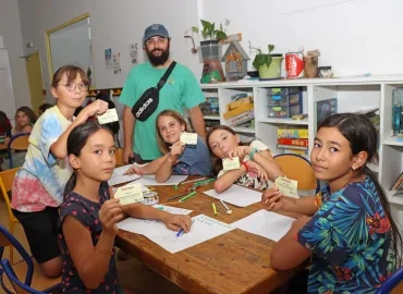un groupe d'enfants et leur animateur pose avec leur carte de presse