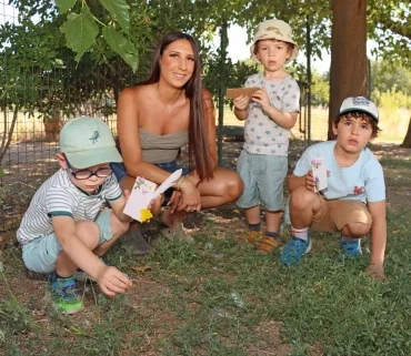 Un groupe d'enfants et leur animatrice montrent des morceaux de carton autocollant avec des éléments naturels collés dessus