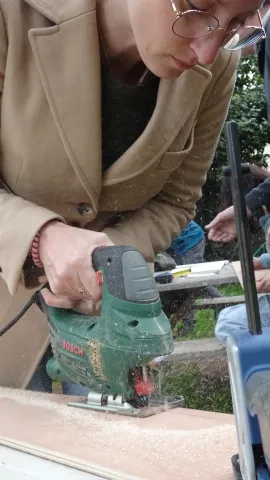 une adulte coupe une plante avec une scie sauteuse