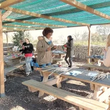 Plusieurs adultes construisent des instruments en bois sur différentes tables en extérieur 