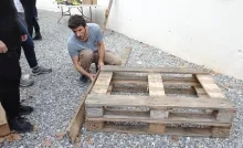 Un animateur finit de monter un carré potager, il est entouré d'adultes