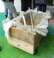 Une jardinière en bois contenant une bache en plastique et un tuyau coupé