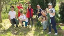Un groupe d'enfants et leur animatrice montrent leur récolte au potager