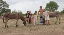Un groupe d'enfants et leur animateur posent avec deux ânes