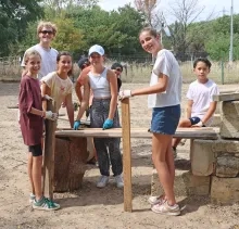 Un groupe d'enfants et leur animateur montrent des planches de bois