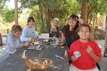 un groupe d'enfants et leur animatrice montrent leurs réalisations avec des morceaux de bois et des glands