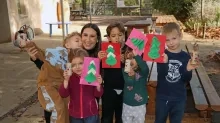 un groupe d'enfants et leur animatrice montrent des cartes en papier avec des sapins