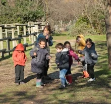 un groupe d'enfants et leur animatrice posent avec un arc en bois