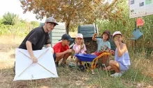 Un groupe d'enfants et leur animateur posent avec des loupes devant des composteurs