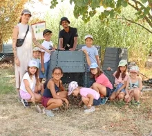 Un groupe d'enfants et leur animateurs posent avec un composteur ouvert
