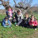 Un groupe d'enfants et leur animatrice cueillent de l'herbe