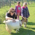deux enfants et leur animateur caressent une chèvre