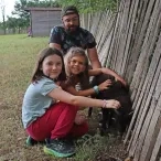 Deux fillettes et leur animateurs sont accroupies près d'un jeune mouton