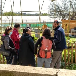 Un agent et un groupe d'adulte observent le jardin des possibles de l'Écolothèque