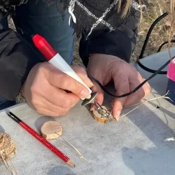 un adulte fait de la pyrogravure sur un petit rondin de bois