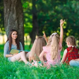 Des enfants lèvent la main et discutent ensemble avec un adulte